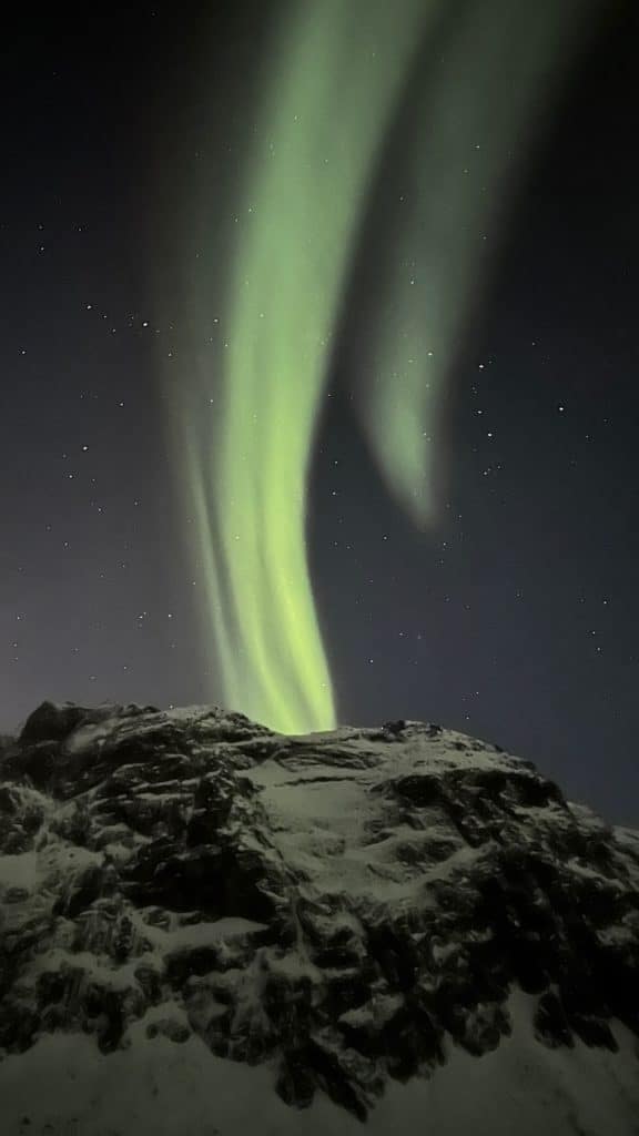 Une aurore boréale au-dessus des montagnes de Tromso sous un ciel étoilé